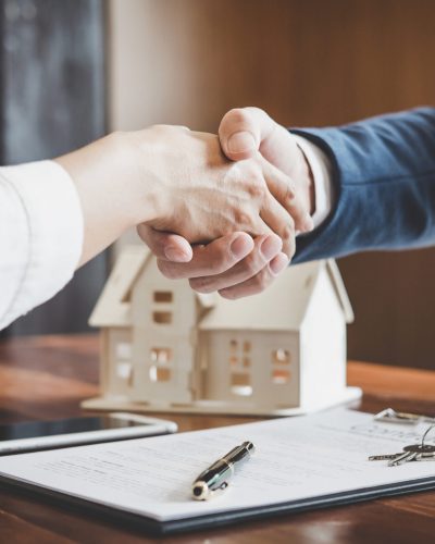 Real estate agent and customers shaking hands together celebrating finished contract after about home insurance and investment loan, handshake and successful deal.