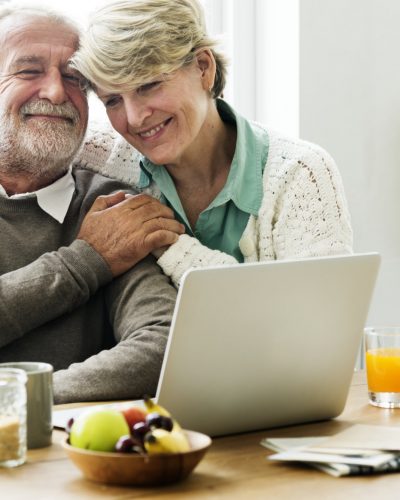 Senior couple hugging while using a laptop